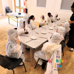 Children dressed in white sitting around table