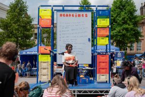 Woman standing on stage with headphones in front of a white board
